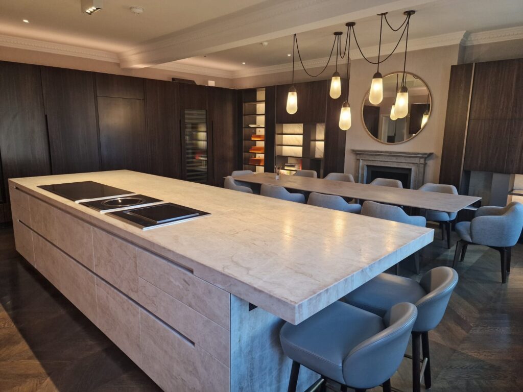 Modern open-plan kitchen and dining area with stone island, pendant lights and upholstered seating