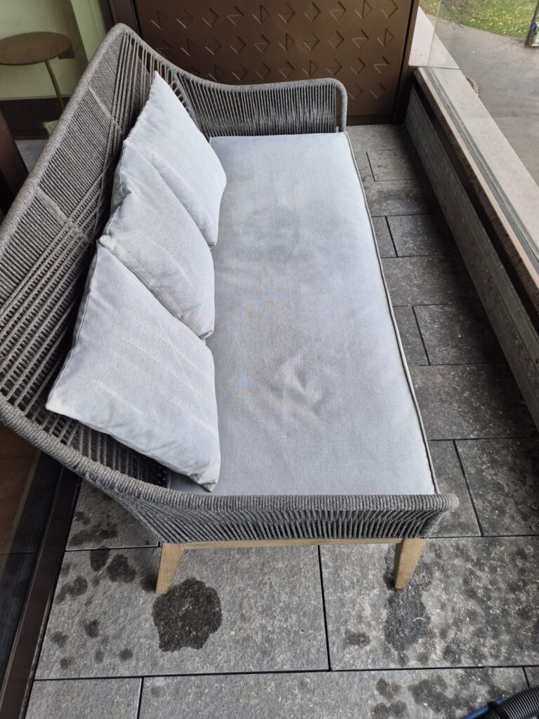 Outdoor balcony bench with light fabric cushions after professional upholstery cleaning