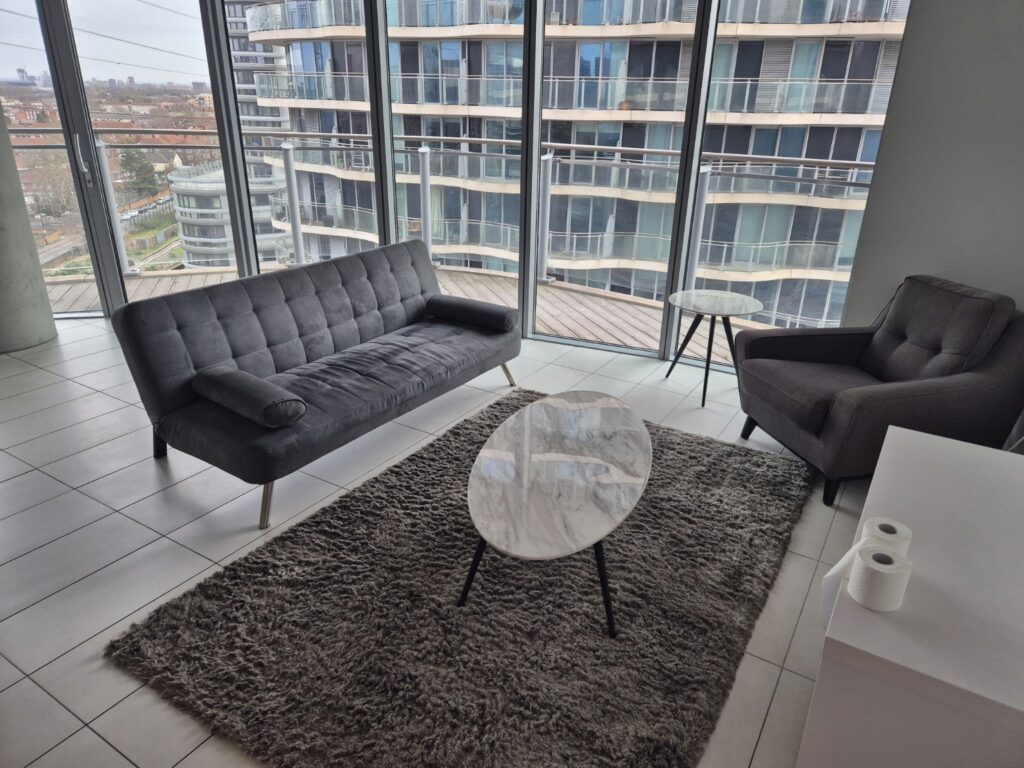 Modern living room after professional cleaning with grey sofa, armchair, shaggy rug and floor-to-ceiling windows