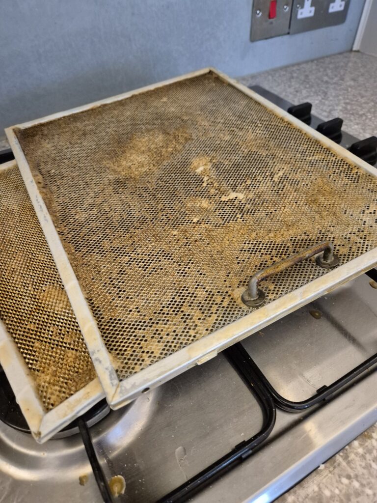 Heavily grease-coated cooker hood filter removed for professional cleaning