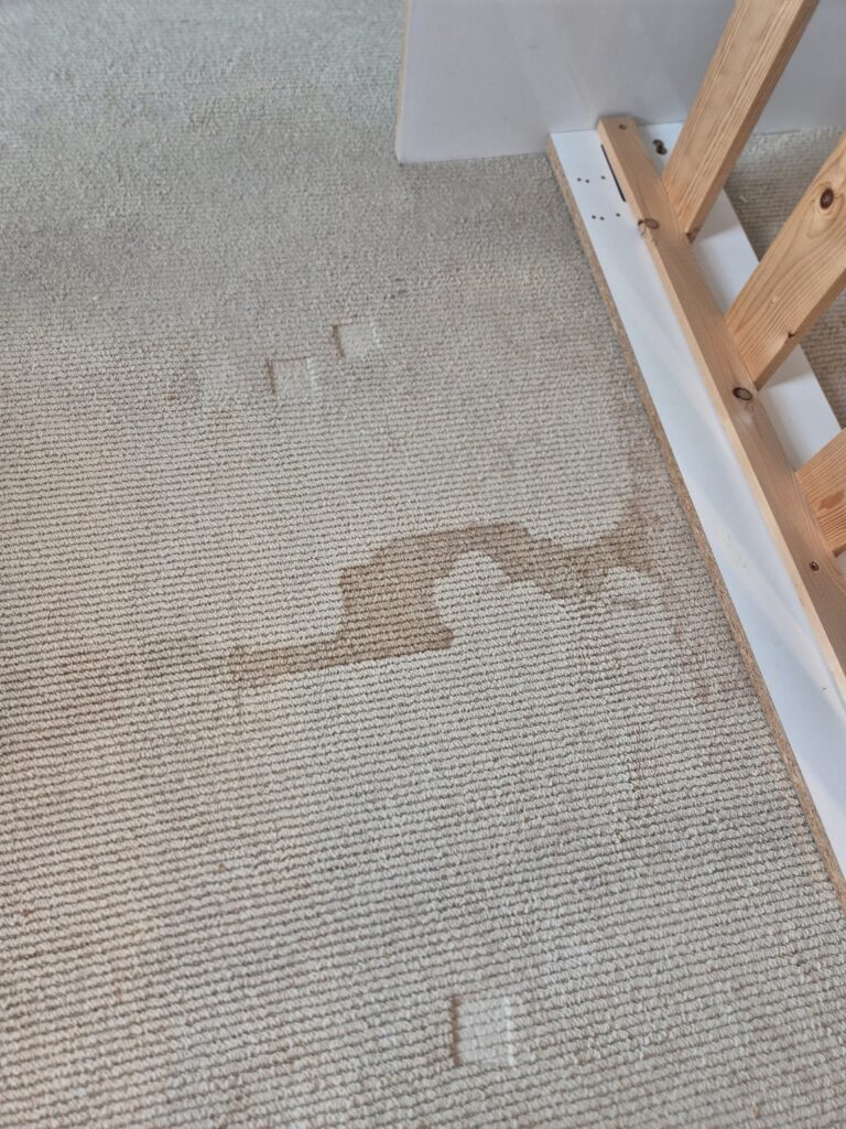 Stained carpet with visible red mark and dirt before professional carpet cleaning