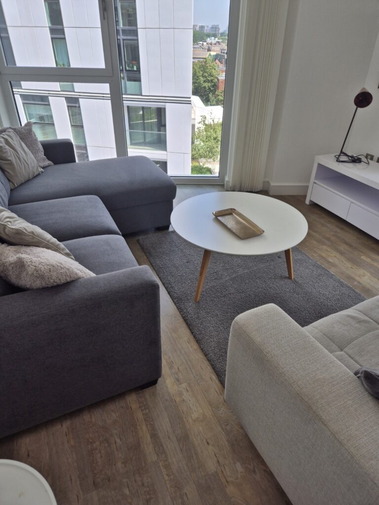 Modern living room with grey sectional sofa, round coffee table and floor-to-ceiling windows