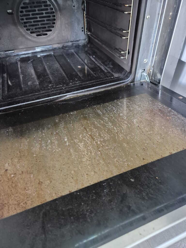 Heavily soiled oven interior and glass door with baked-on grease and residue
