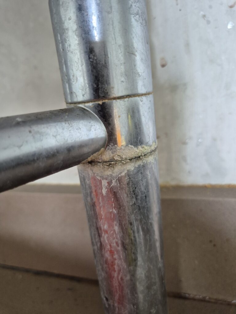 Close-up of heavily soiled chrome water tap with built-up limescale and grime around the base