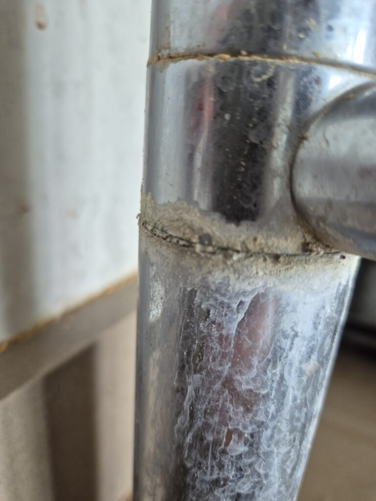 Close-up of heavily soiled chrome water tap with built-up limescale and grime.