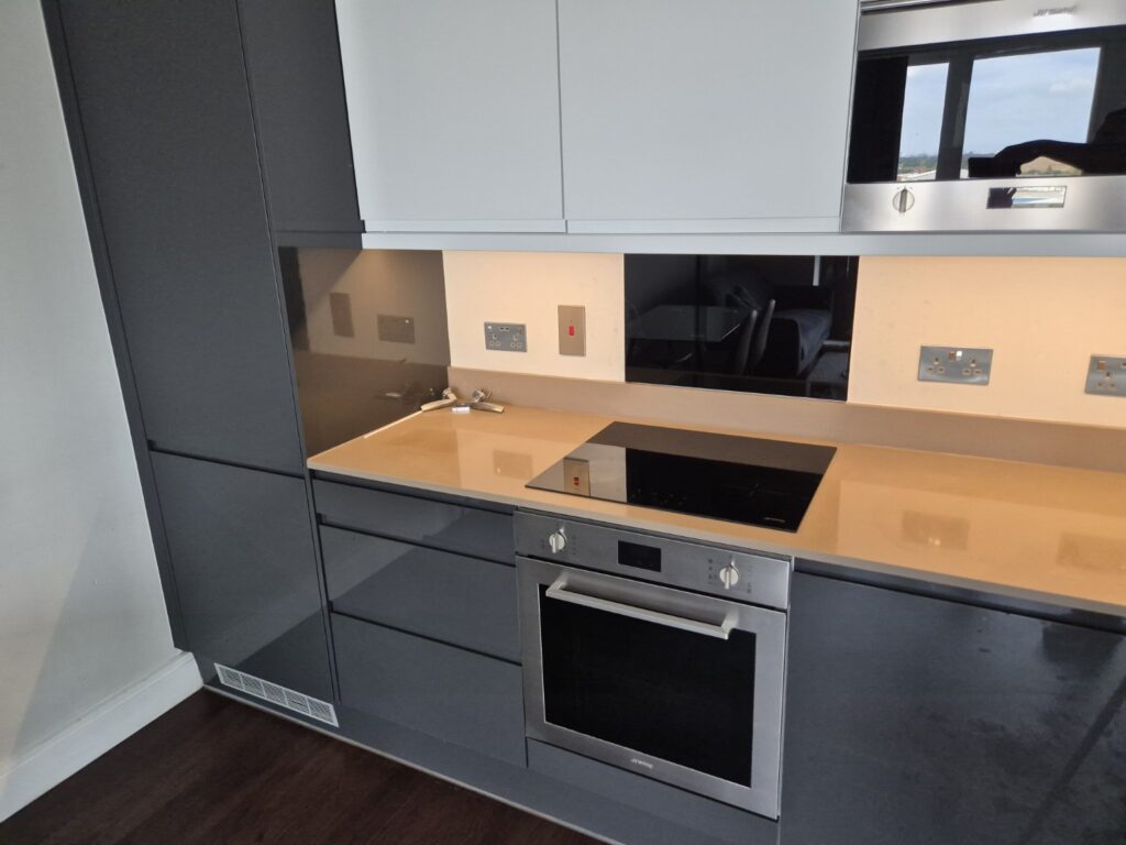 Modern fitted kitchen after professional cleaning with induction hob, built-in oven, worktops and dark cabinetry