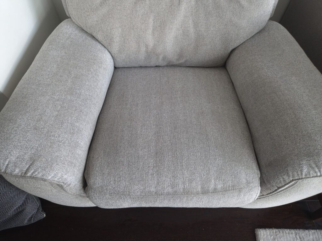 Light grey upholstered armchair after professional upholstery cleaning, showing refreshed fabric and visible extraction lines