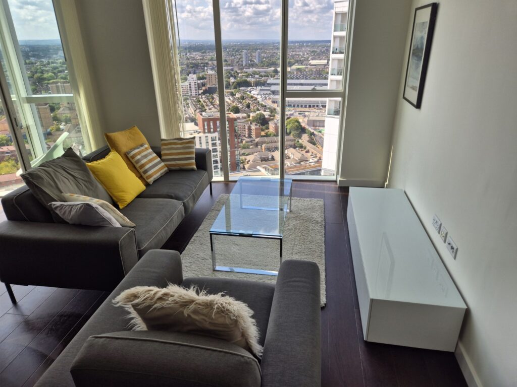 Modern living room after professional cleaning with grey sofas, glass coffee table and floor-to-ceiling windows