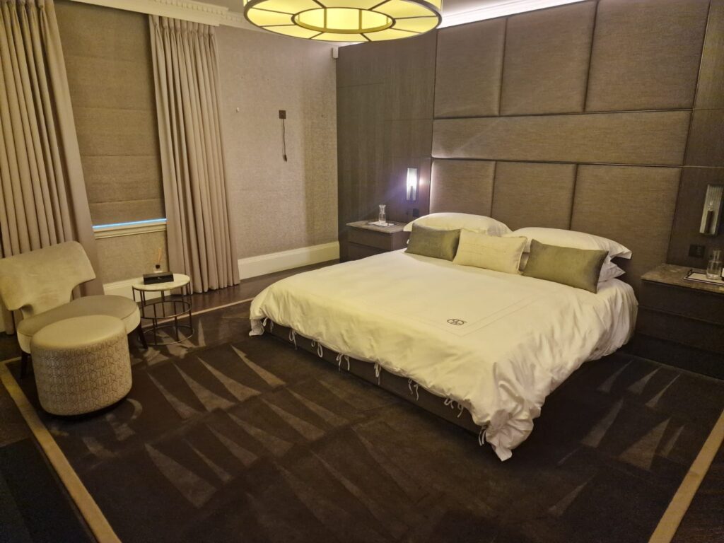 Modern bedroom after professional cleaning with upholstered wall panels, double bed, bedside tables and carpeted flooring