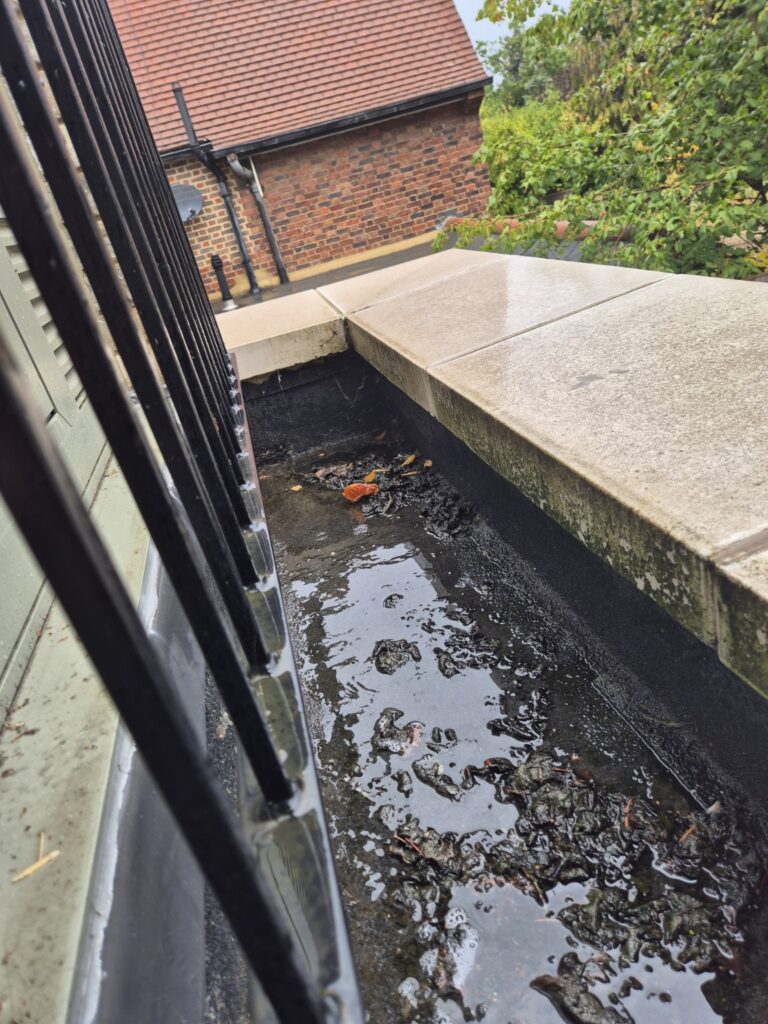 Balcony gutter before cleaning with standing water, heavy dirt, debris and algae build-up