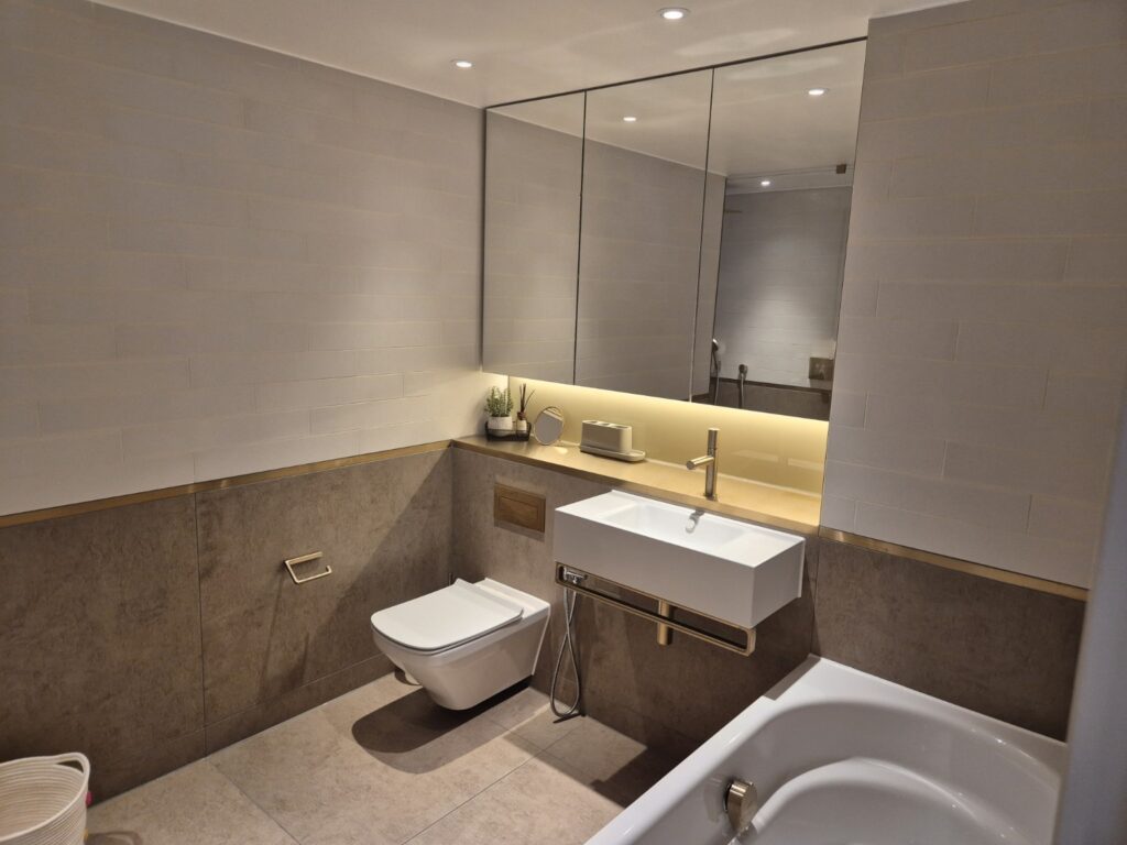 Modern bathroom after professional cleaning with wall-mounted toilet, basin, bathtub and mirrored cabinets