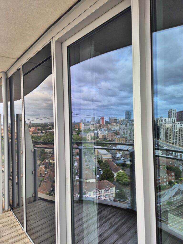 Floor-to-ceiling balcony windows and glass doors after professional cleaning, with clear city views
