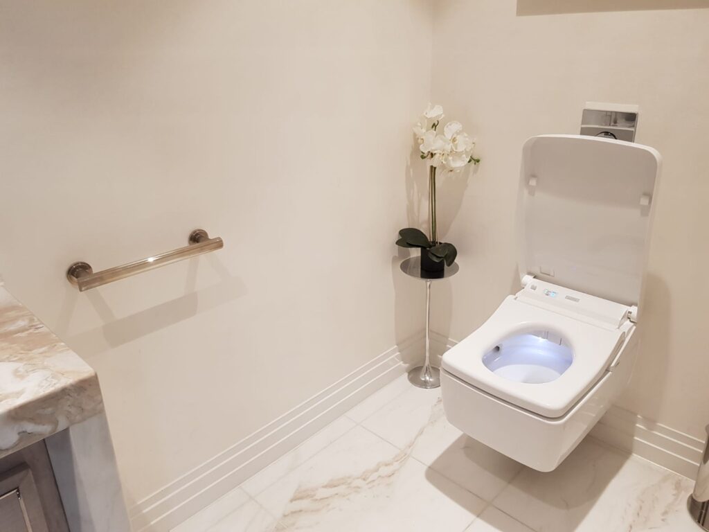 Modern bathroom after professional cleaning with wall-mounted toilet and marble flooring.